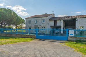 A building with a stone facade, a blue gate, and a sign indicating a business. - Group Gite with Indoor Pool, Private Terrace, Garden, and Wi-Fi (La Gripperie-Saint-Symphorien)