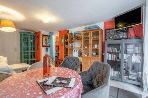 Un soggiorno con tavolo, sedie, libreria e televisione.