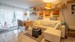 A living room with a sofa, coffee table, and a dining area with a table and chairs. - Apartment 'Le Grand Lapin Blanc' with Sea View, Private Terrace and Wi-Fi (Fleury)