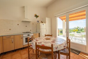 A kitchen with wooden cabinets, a white refrigerator, and a dining table with chairs.