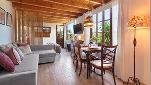A living room with a sofa, dining table, chairs, a TV, and a lamp.