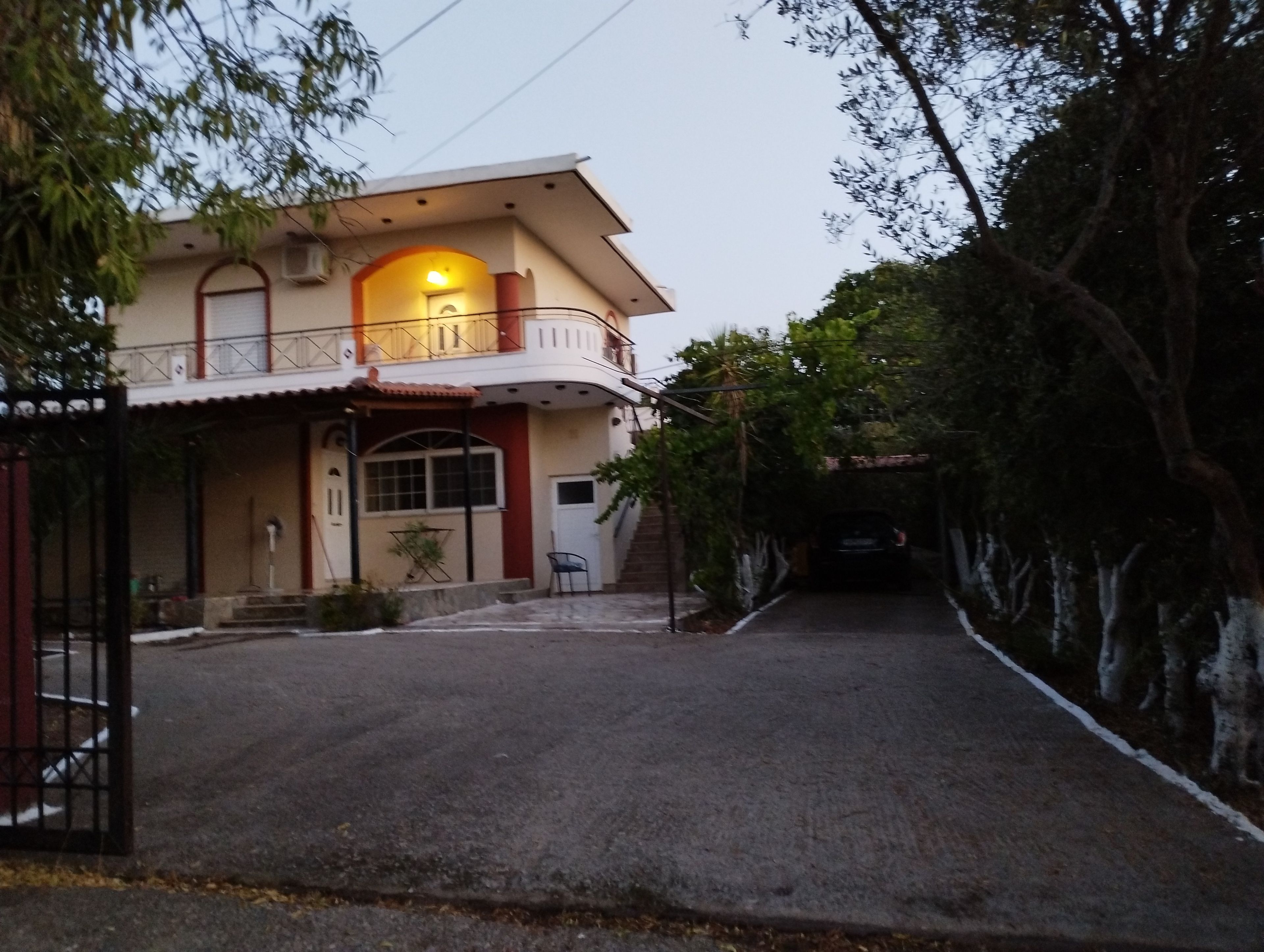 A two-story house with a balcony, a driveway, and a car parked inside.