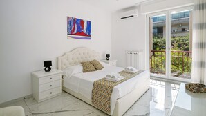 Ein Schlafzimmer mit Bett, Nachttischen, einem Fenster mit Blick und einem Bild an der Wand.