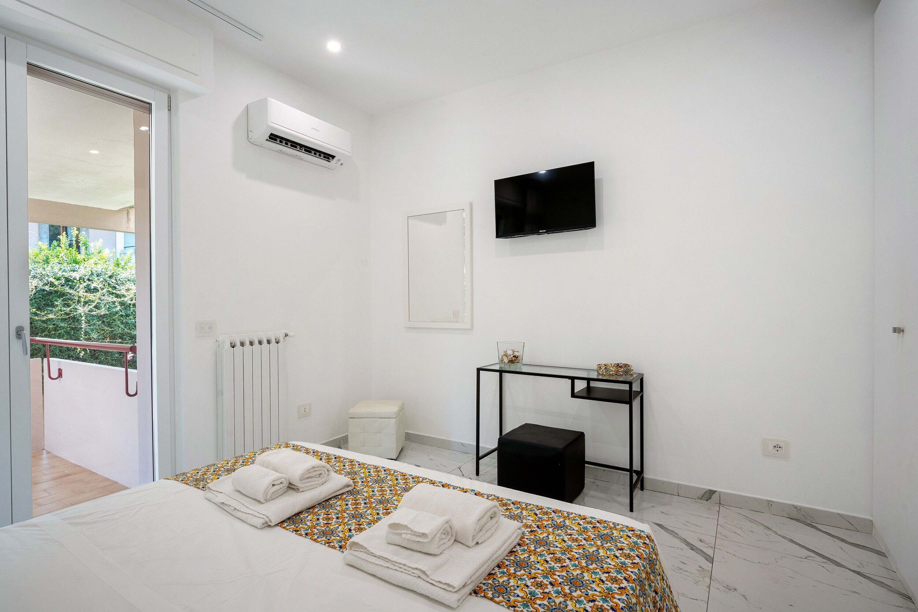 Habitación de hotel con cama, aire acondicionado, televisor, una mesita y radiador.