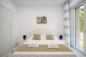 Une chambre à coucher avec un lit, deux tables de chevet, une fenêtre avec des rideaux et un tableau accroché au mur.