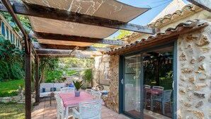 An outdoor patio with a table and chairs, a pergola, and a stone wall.