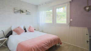 Une chambre à coucher comprenant un lit, une fenêtre, un radiateur et un élément décoratif fixé au mur.