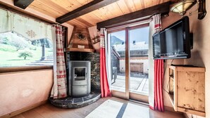 Une pièce confortable avec une cheminée, un téléviseur et une vue sur l’extérieur.