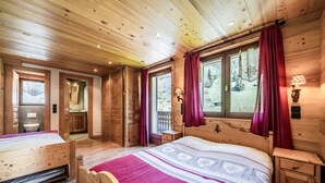 Une chambre dans une cabane en bois, avec un lit, une table de chevet, une fenêtre avec des rideaux et une vue sur l’extérieur.