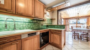 Une cuisine avec des meubles en bois, un plan de travail recouvert de carreaux verts, un lave-vaisselle et un four.