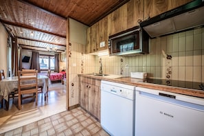 A kitchen with wooden cabinets, a Bosch dishwasher, a microwave, and a dining area with a table and chairs.