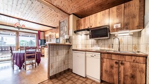 A kitchen with wooden cabinets, a microwave, a dishwasher, and a dining area with a table and chairs.