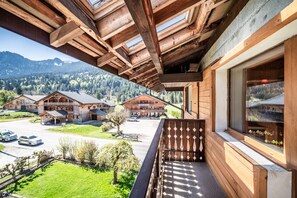 Un balcon en bois offrant une vue sur un paysage montagneux, un bâtiment en bois doté d’un balcon et un ciel dégagé.