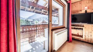 A room with a large sliding glass door, wooden ceiling, a built-in TV shelf, and a radiator.