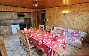 Un intérieur en bois comprenant une table à manger pour quatre personnes, un canapé et un coin cuisine.