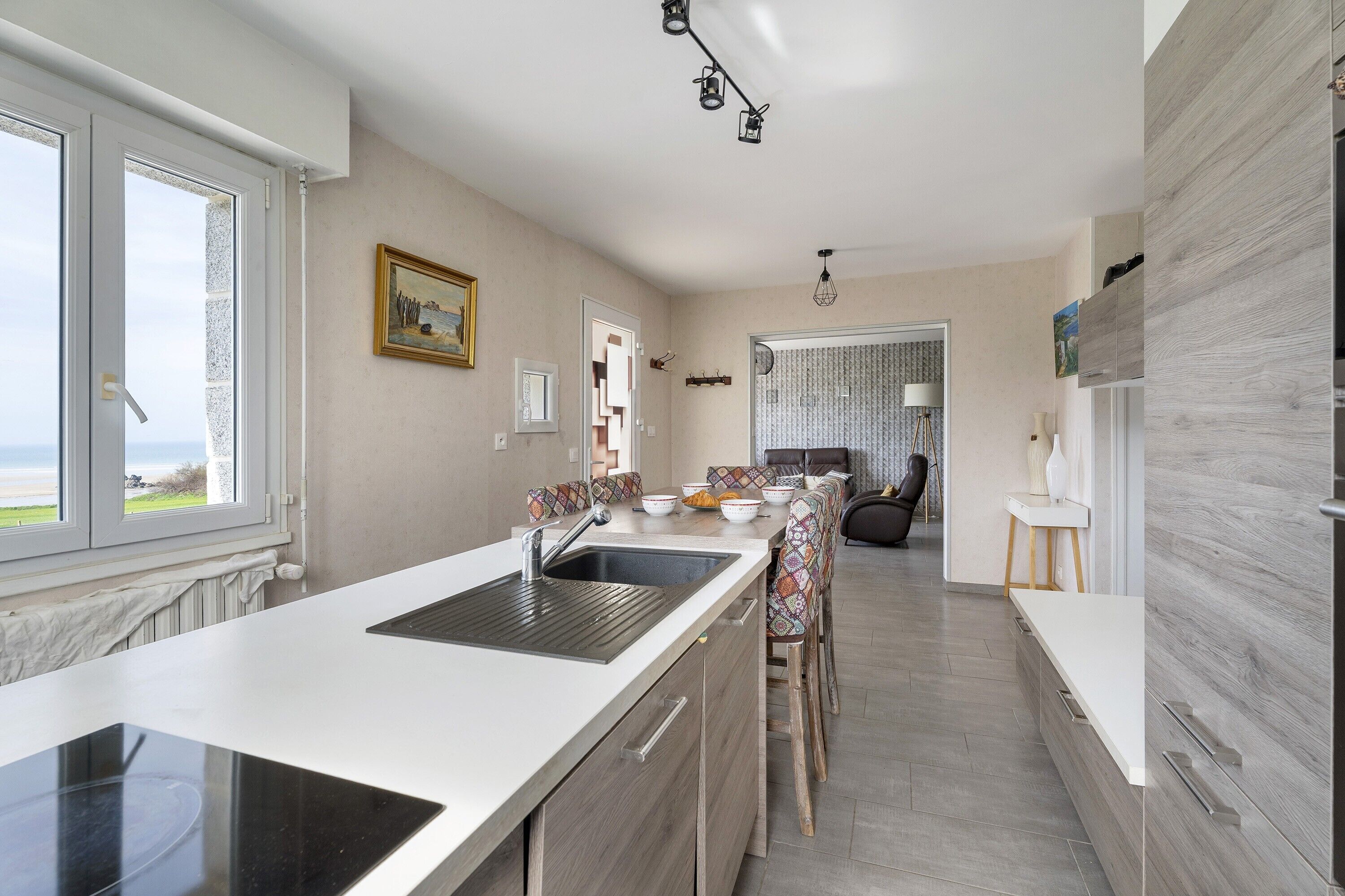 Une cuisine moderne dotée d’un grand îlot central, d’un coin repas avec des chaises à motifs et d’une vue par la fenêtre.