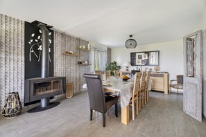 Uma área de refeições moderna com lareira, mobiliário de madeira e prateleiras decorativas.