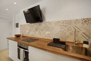 Una cocina moderna con encimera de madera, pileta de acero inoxidable y televisor montado en la pared.