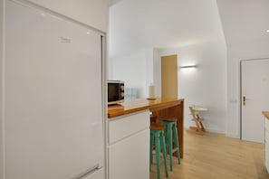 Una kitchenette con microondas, mostrador de madera y taburetes de bar.