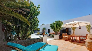 A patio with lounge chairs, a table, and umbrellas. - 'Villa La Cueva' with Shared Pool, Private Terrace and Wi-Fi (Teguise)