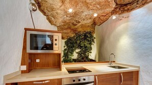 A kitchen with a stone wall, wooden cabinets, a built-in oven, and a sink. - Vacation Villa 'El Cactus' with Shared Pool and Wi-Fi (Teguise)