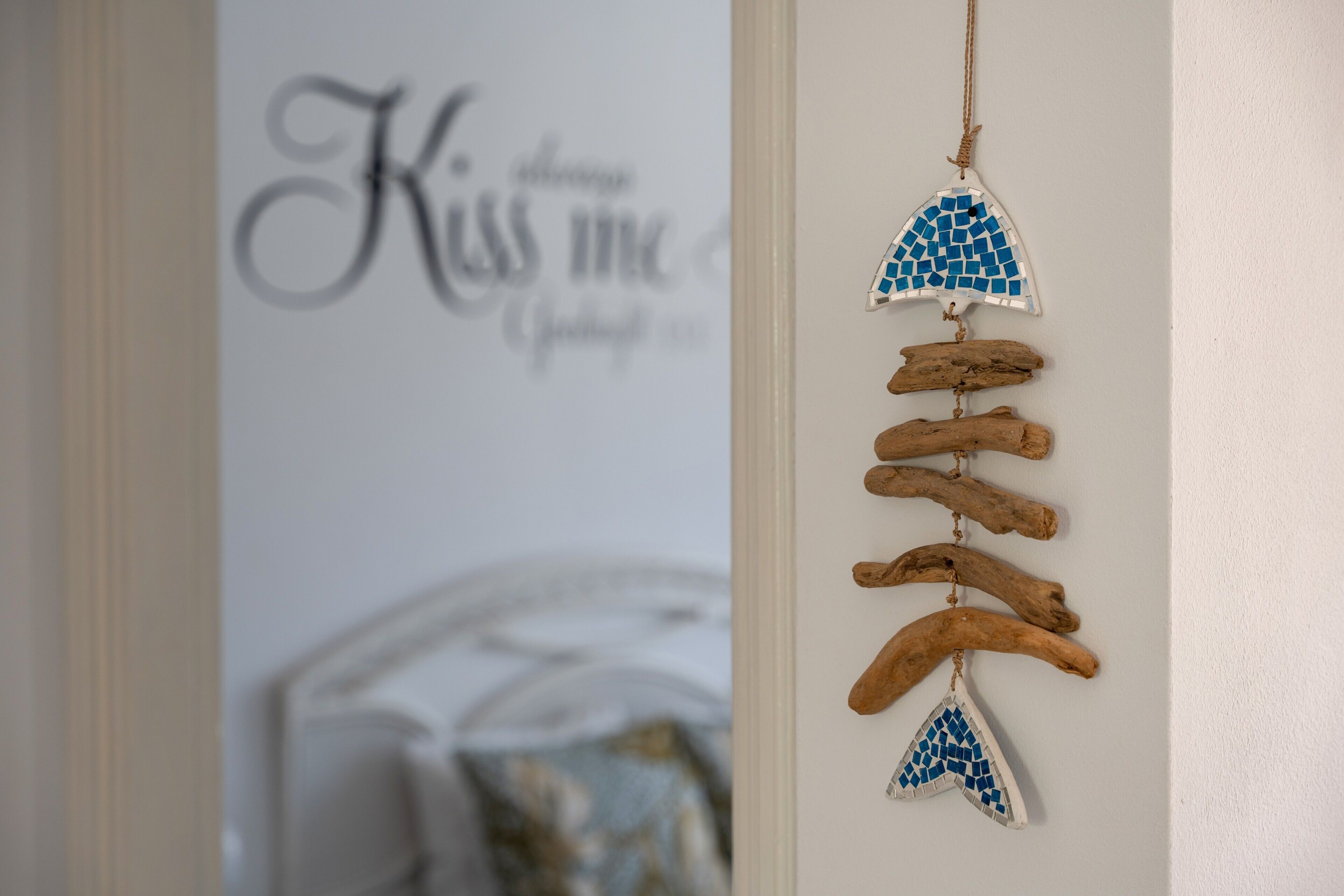 Een wand met een decoratieve wandhanger van drijfhout en mozaïektegels.