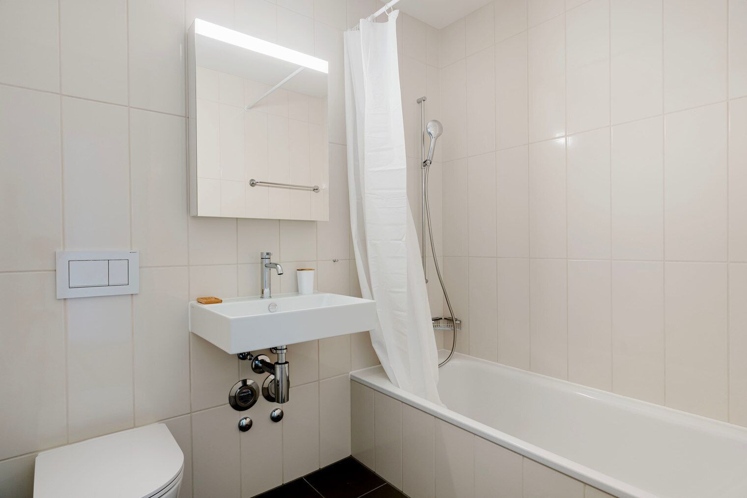 A bathroom with a white bathtub, a sink with a mirror above it, and a shower with a curtain.
