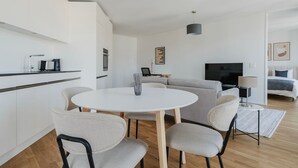 Un soggiorno moderno con un tavolo da pranzo rotondo, divani grigi e una TV a schermo piatto.
