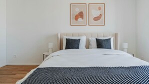 Una camera da letto con un letto, due comodini e due dipinti astratti appesi al muro.