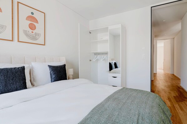 A modern bedroom with a bed, a wardrobe, and a mirror.