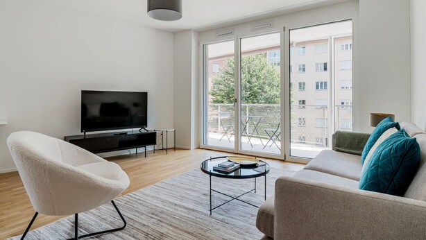 A modern living room with a flat-screen TV, a sofa, a chair, and a coffee table.