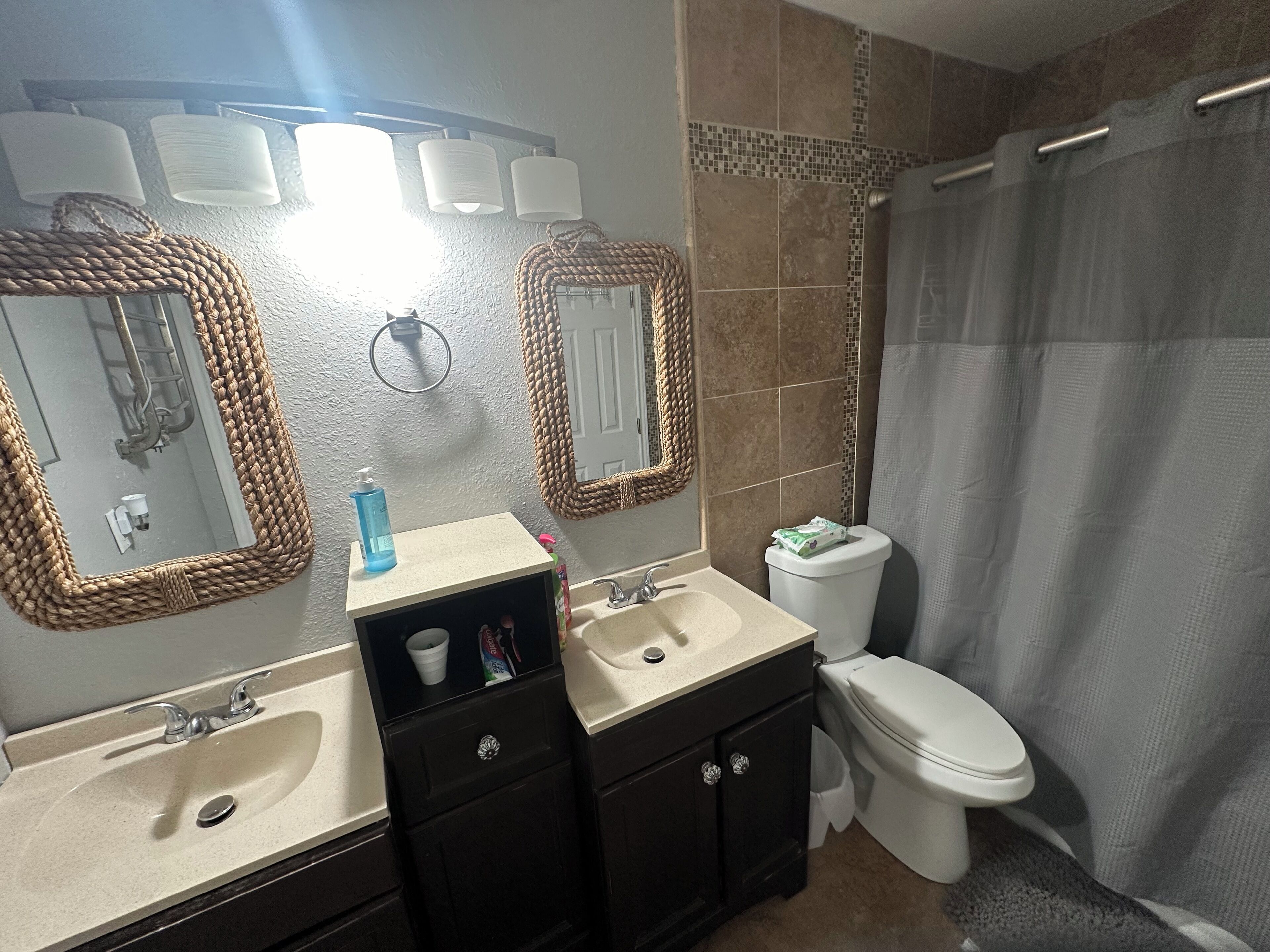 Un baño con lavamanos, espejo, inodoro y cortina de ducha.