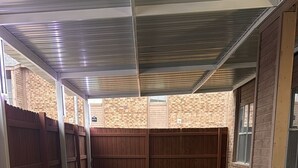 Un espacio al aire libre techado con césped artificial verde y losas de piedra.