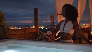 Eine Frau sitzt am Pool mit Blick auf die Stadt.