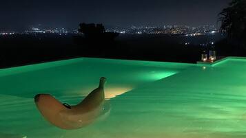 An infinity pool with a view of a cityscape at night.