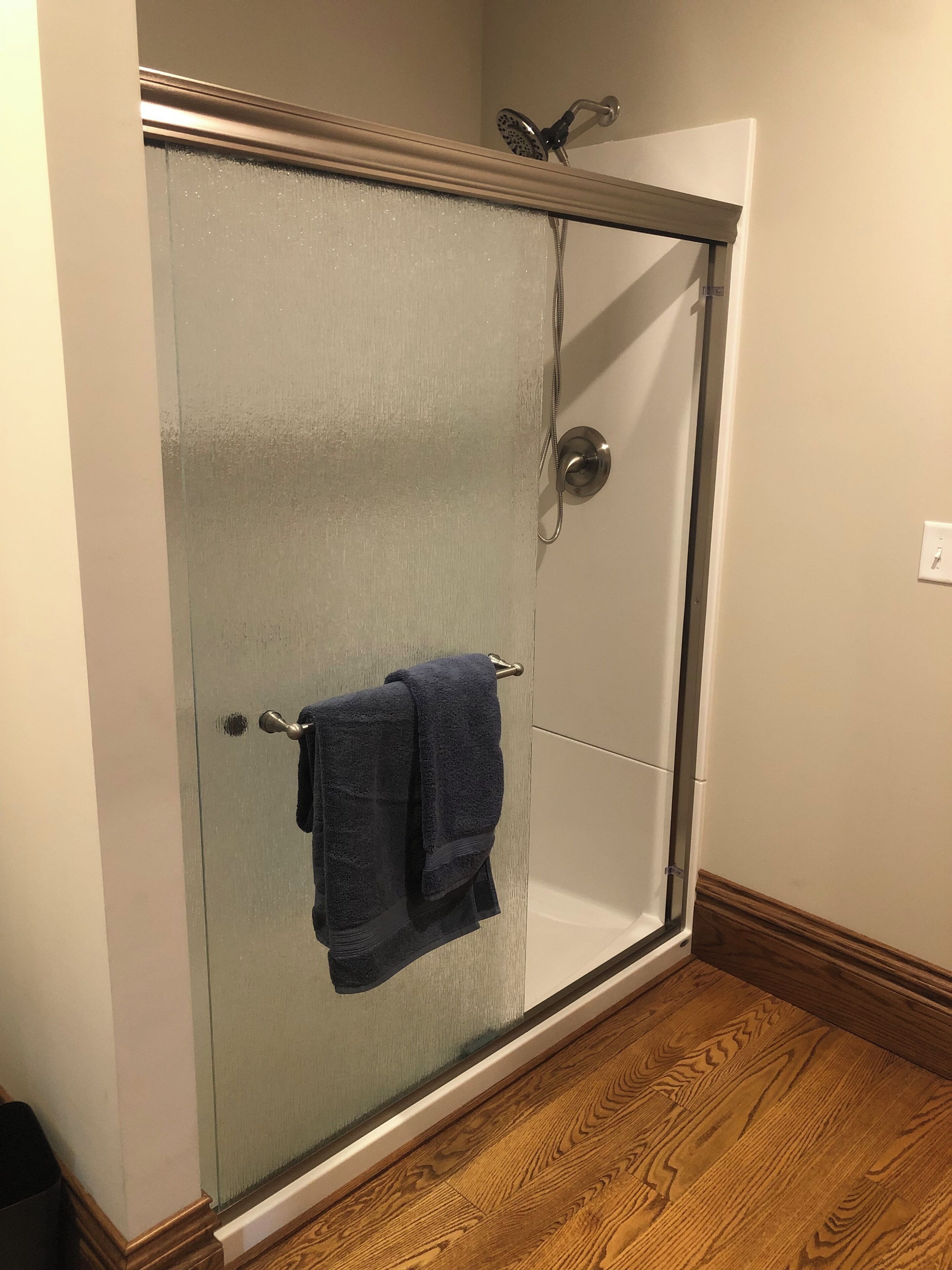 A glass-enclosed shower with a towel hanging on the door handle.