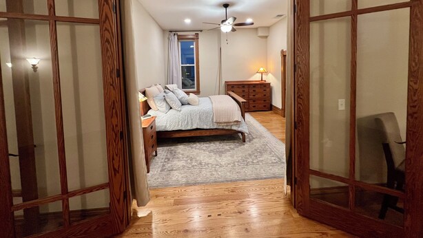 A bedroom with a bed, bedside table, lamp, and a view of the adjacent room through a wooden-framed door. - Spacious 2-bedroom loft above the International Owl Center in Houston, MN (Houston)