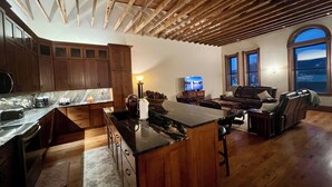 A spacious living area with a wooden ceiling, a kitchen with a marble countertop, and a large window overlooking a snowy landscape. - Spacious 2-bedroom loft above the International Owl Center in Houston, MN (Houston)