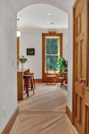 Un pasillo con piso de madera, una puerta de madera y una ventana con vistas a árboles.