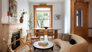 Una sala de estar con chimenea, una mesa de comedor con sillas, un sofá y un ventanal grande.