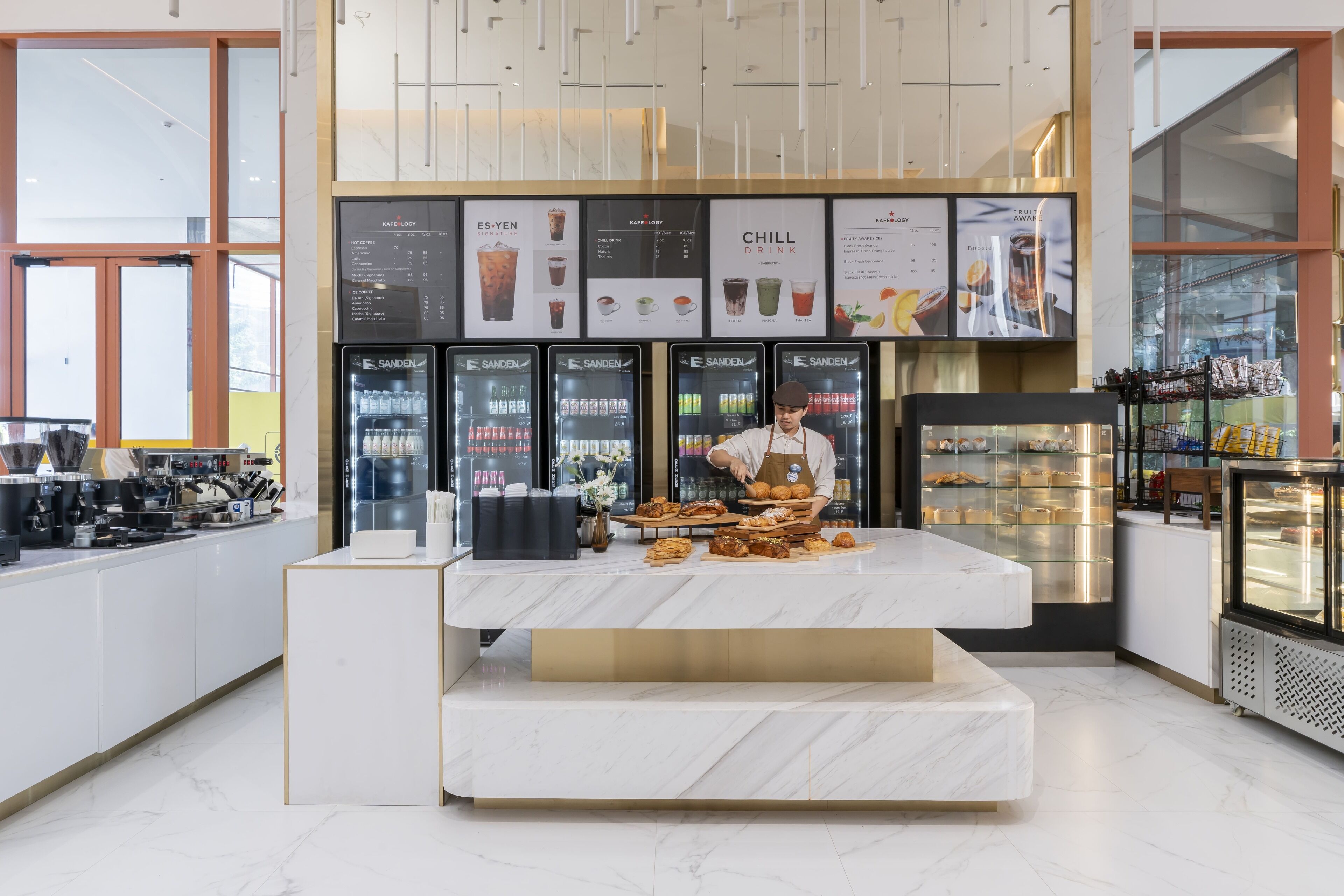 A modern café interior with a marble counter, refrigerated display cases, and menu boards.