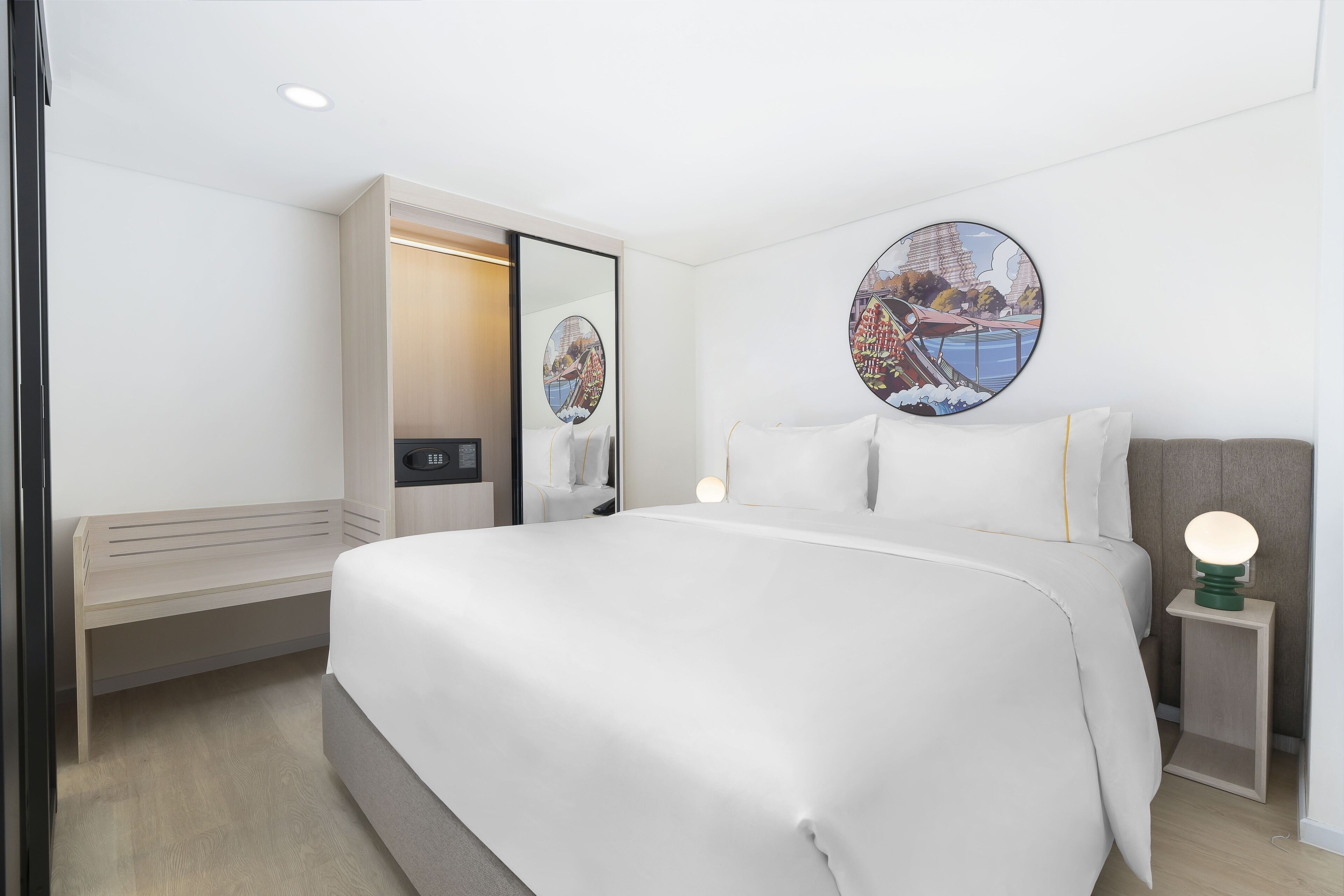 Ein modernes Hotelzimmer mit einem großen Bett, einem Nachttisch mit Lampe, einem Spiegel und einem Wandbild.