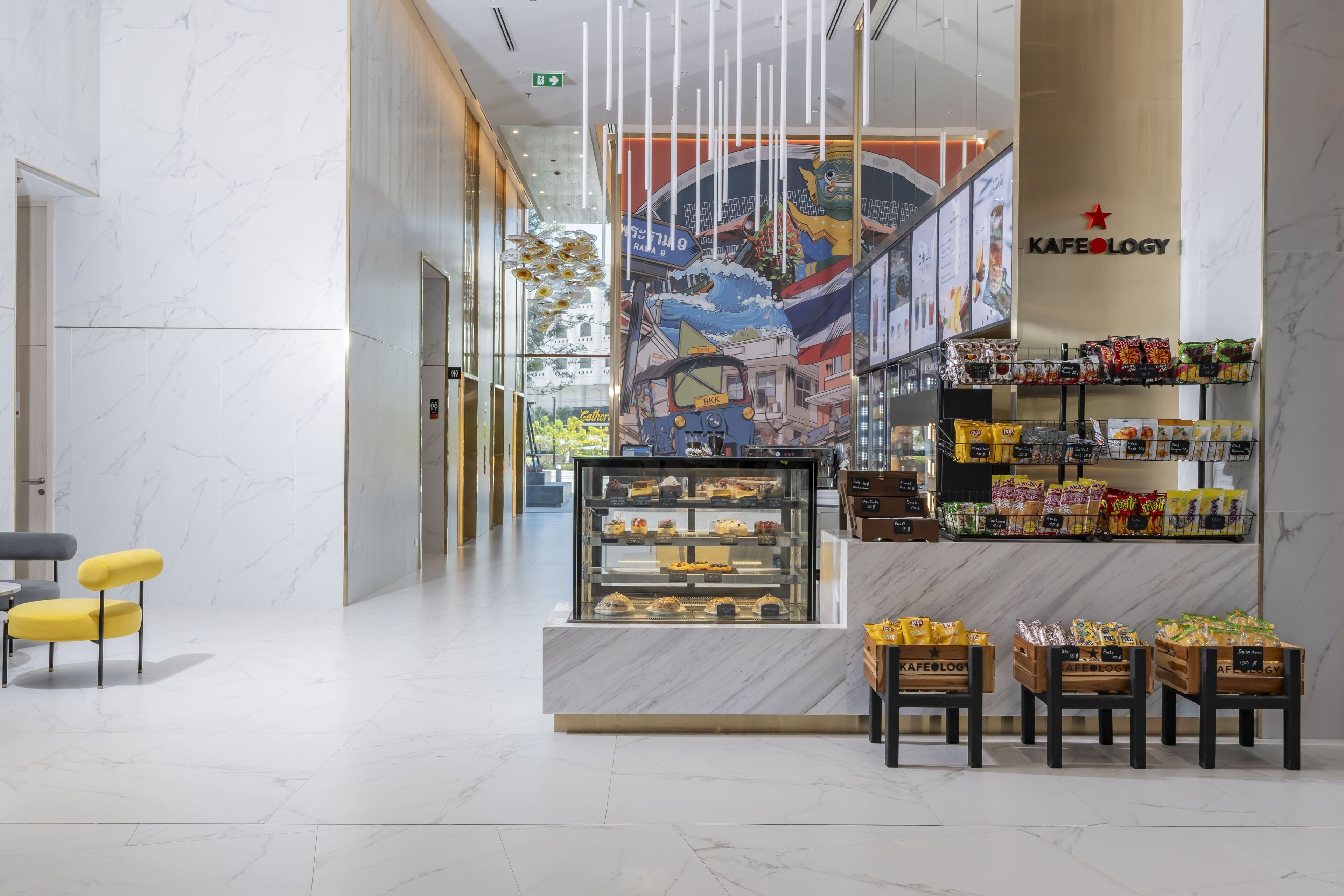 A modern interior with a marble floor, a Kafeology counter with snacks, and a mural.