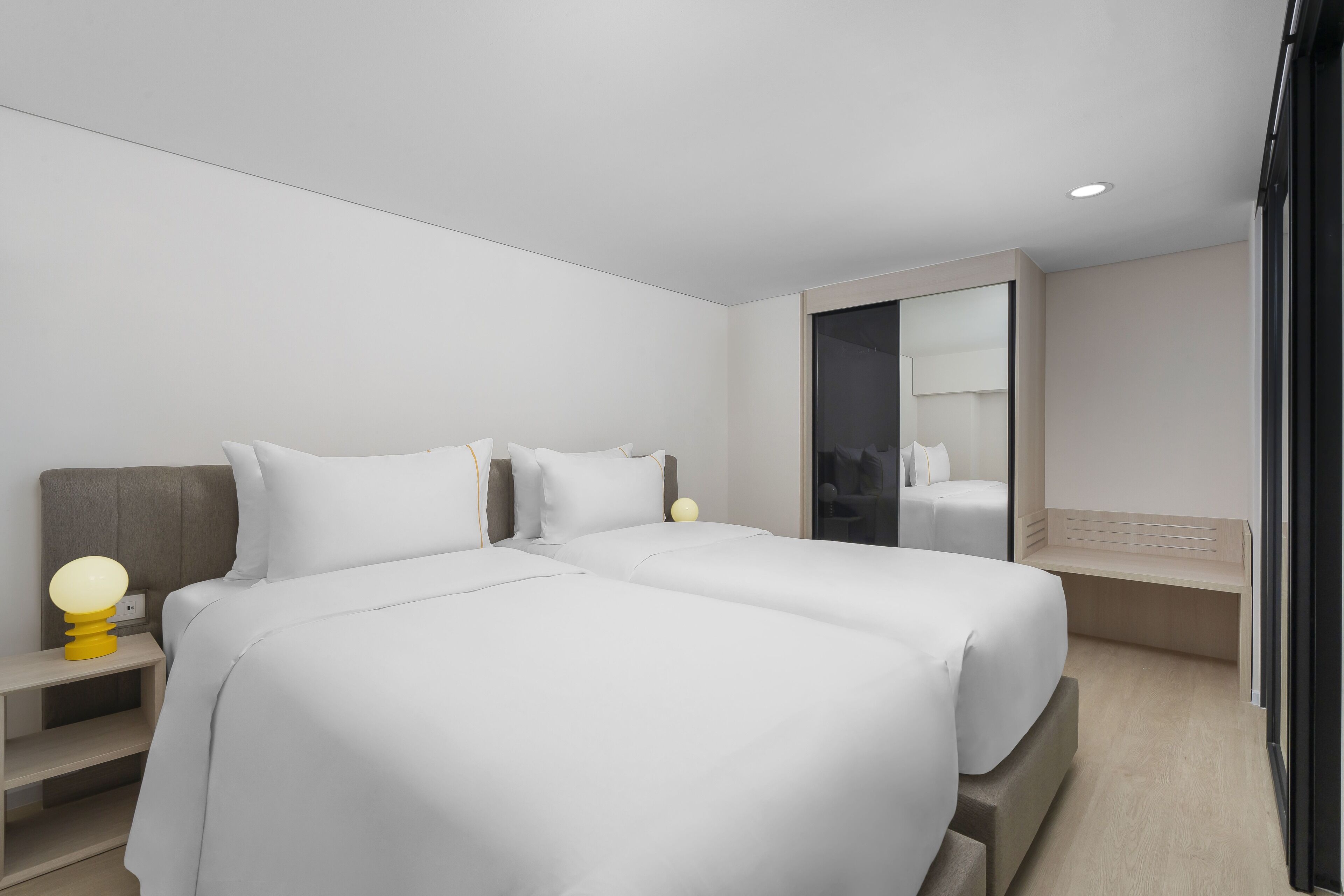 Et moderne hotelværelse med en stor seng, sengeborde og et spejl.