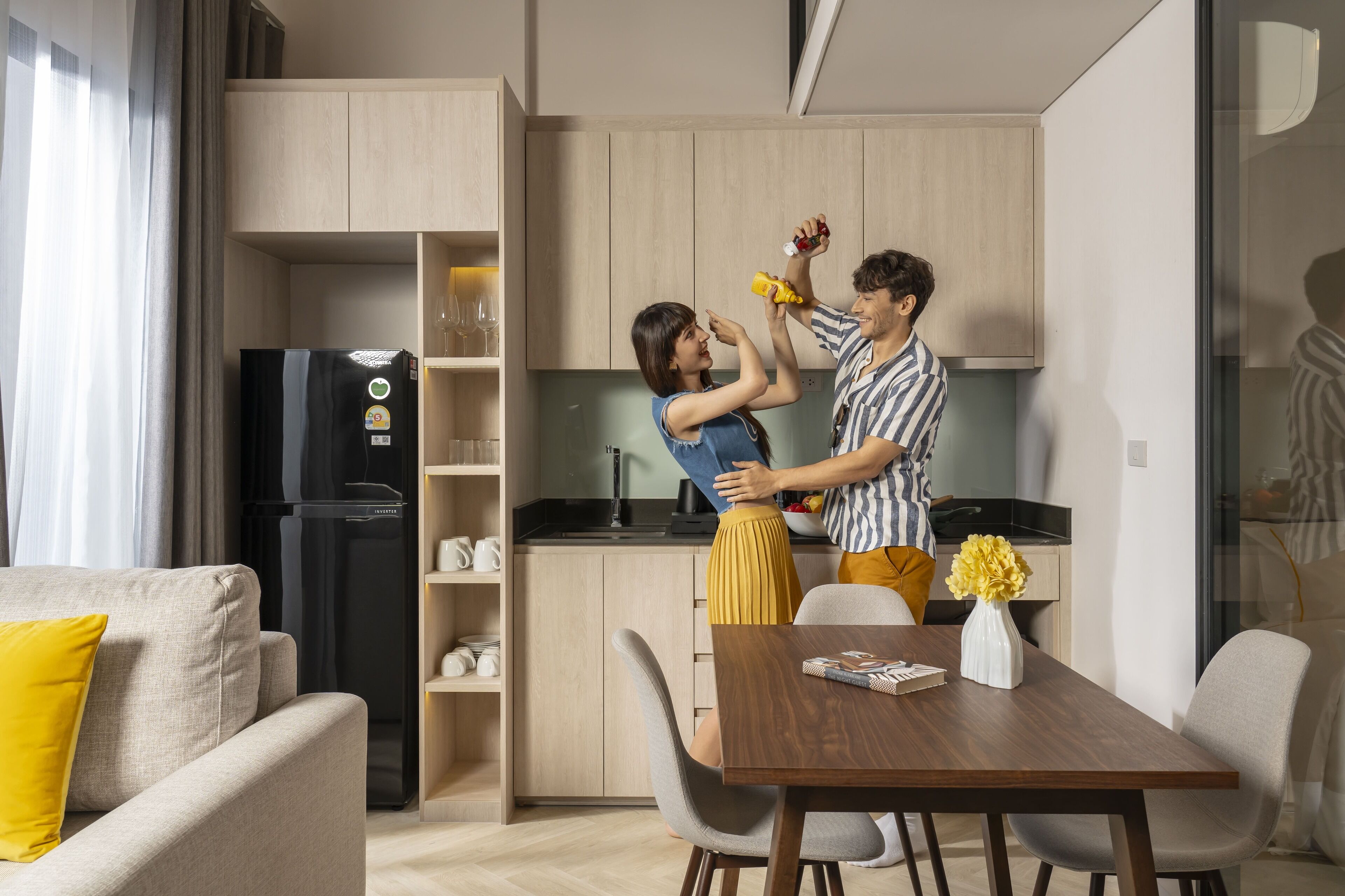 Eine moderne Küche mit Holzausstattung, einem schwarzen Kühlschrank und einem Essbereich mit Holztisch und Stühlen.