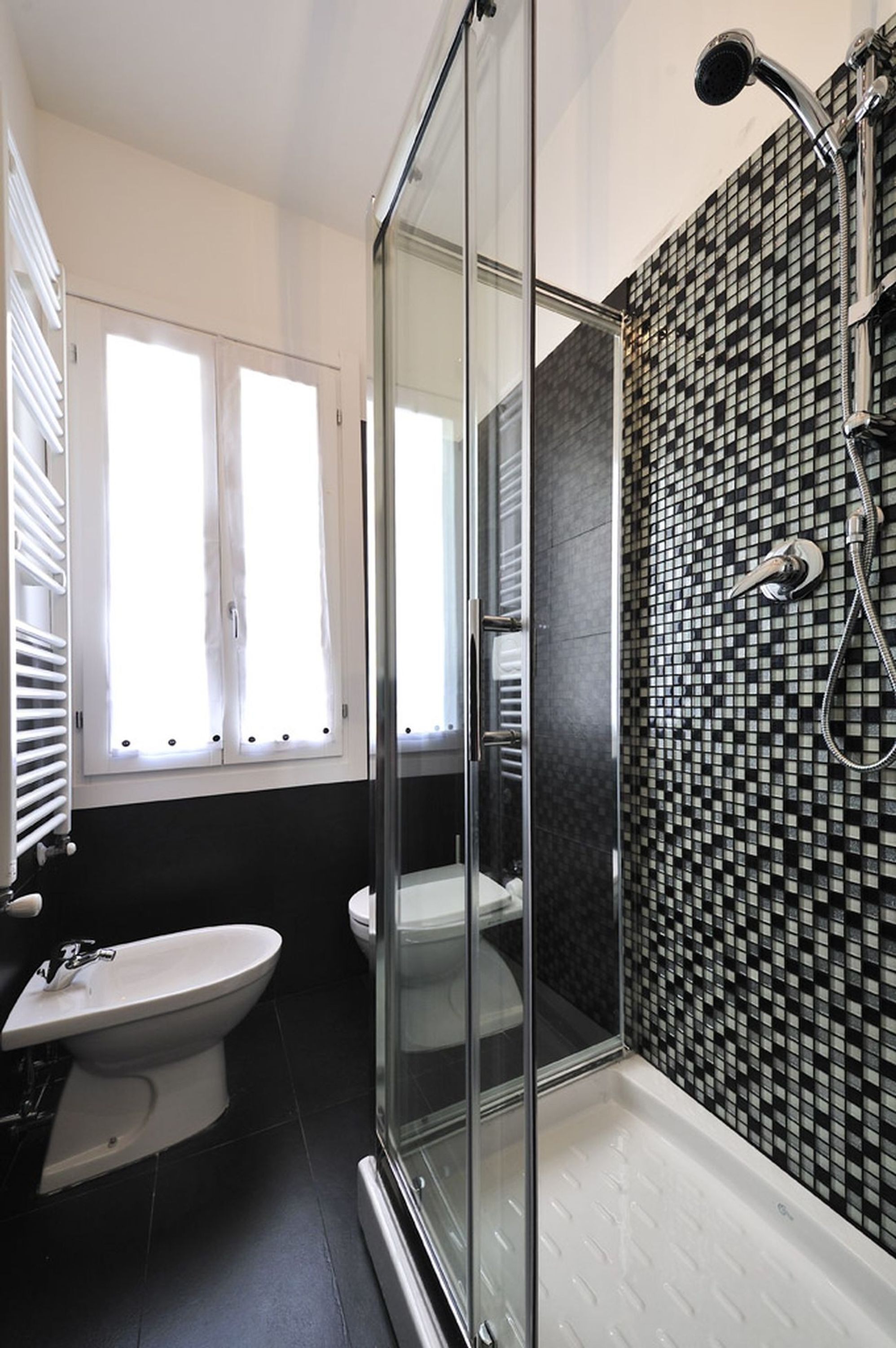 A modern bathroom with a glass shower enclosure, a toilet, and a bidet.