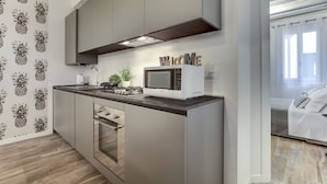 Een moderne keuken met roestvrijstalen apparatuur, een ingebouwde oven en een magnetron. Boven de magnetron hangt een bord met een welkomstboodschap, en de keuken heeft een donker aanrecht en lichtkleurige kastjes.