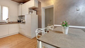 A modern kitchen with white cabinets, a built-in microwave, and a dining area with a table and chairs. - San Marco Promenade by Wonderful Italy (Venice)
