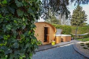 A wooden cabin with a door, a hot tub, and a hammock.