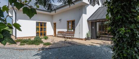 A modern house with a gravel driveway, a bench, and a small garden area.